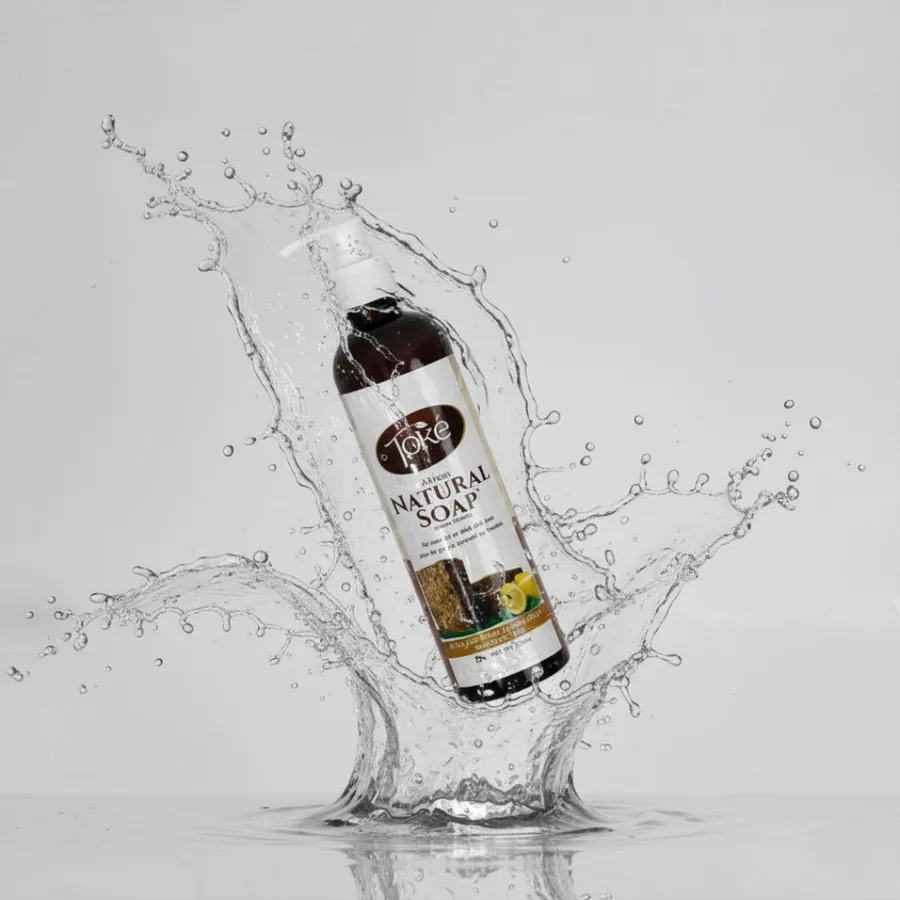 A bottle of Toke Natural Soap in a splash of water